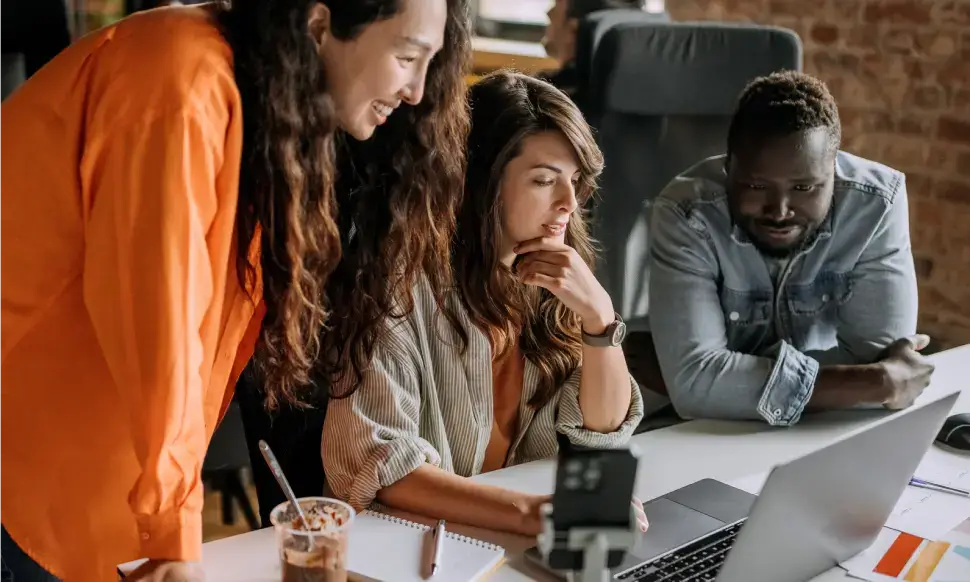 A group of colleagues looking a laptop.